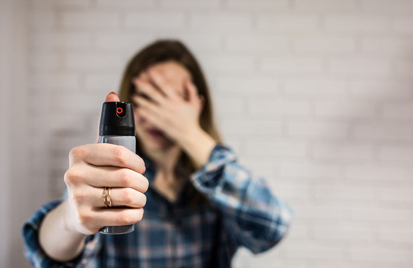 holding pepper spray covering eyes